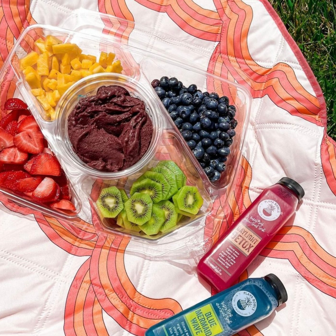 A spread of Playa Bowls and drinks on a blanket