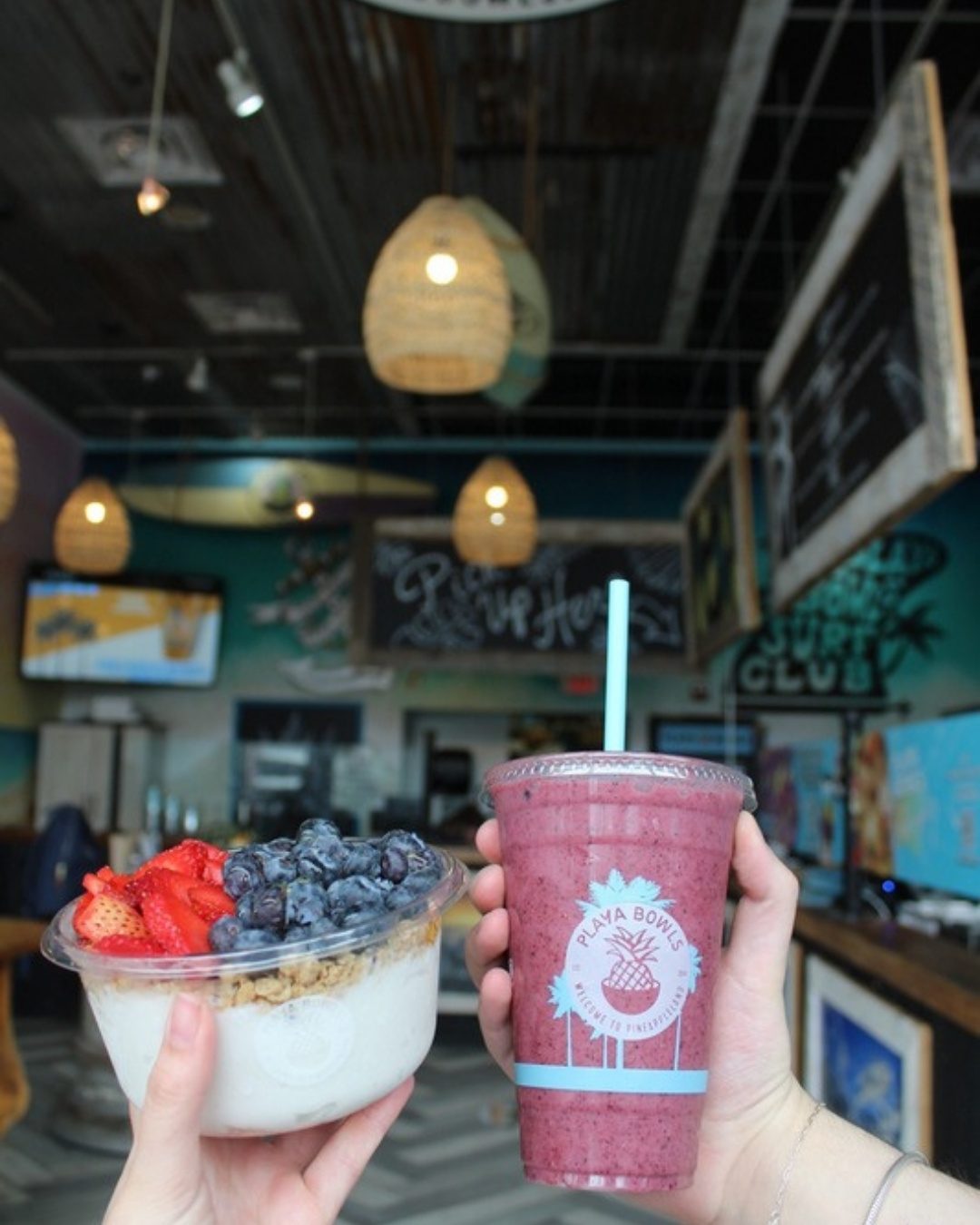 Inside a Playa Bowls shop with surfboards and a beach mural