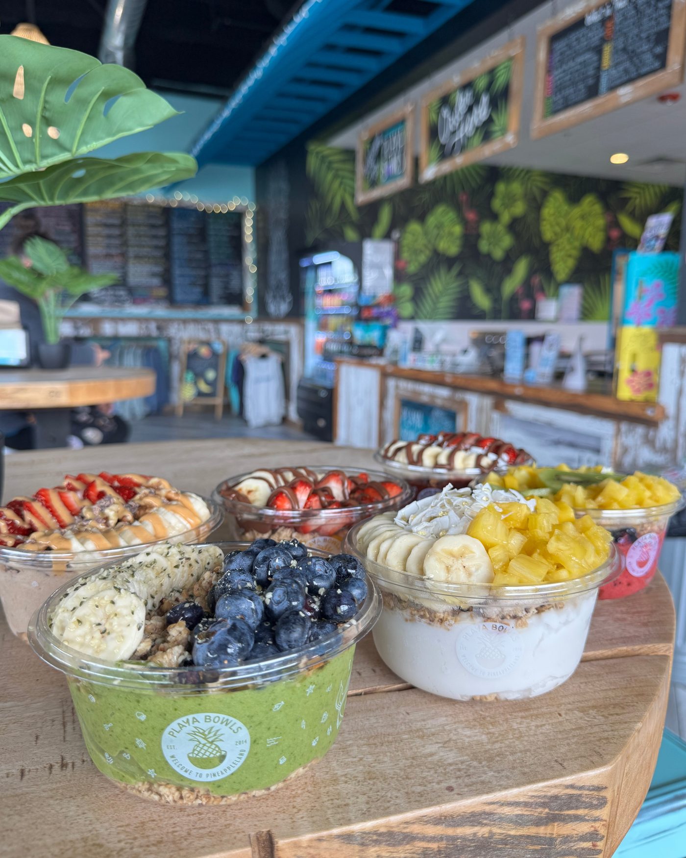 Three Playa Bowls on an outdoor table: acai, pitaya and coconut bases with fruit and granola